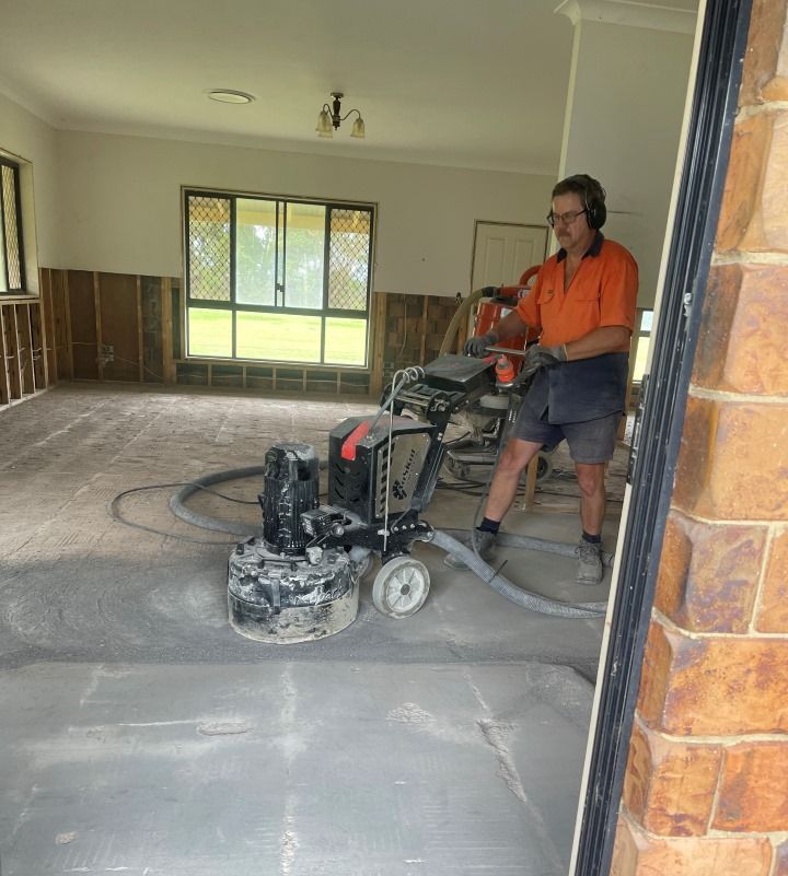 A Man is Using a Grinder on a Concrete Floor in a Room — Goat Collective in Tintenbar, NSW