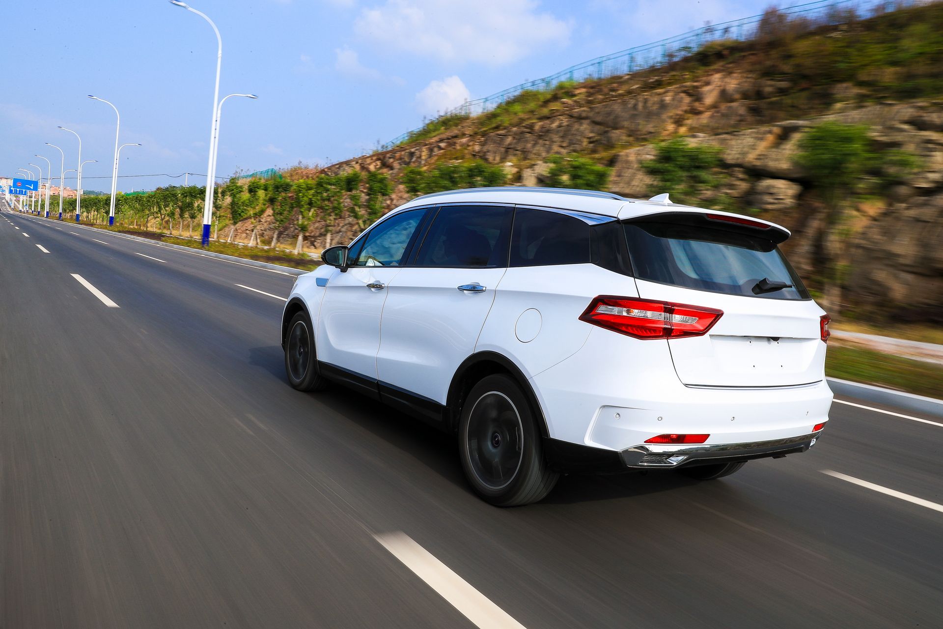 White SUV Driving on a Multi-lane Highway Near a Hill on a Sunny Day — Albury Super Cheap Car Rentals in Lavington, NSW