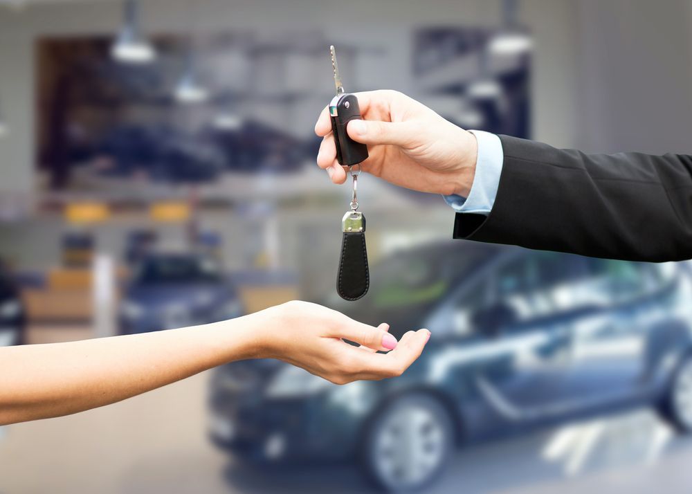 Hand Holding Car Keys Being Passed to Another Hand in a Car Dealership — Albury Super Cheap Car Rentals in Lavington, NSW