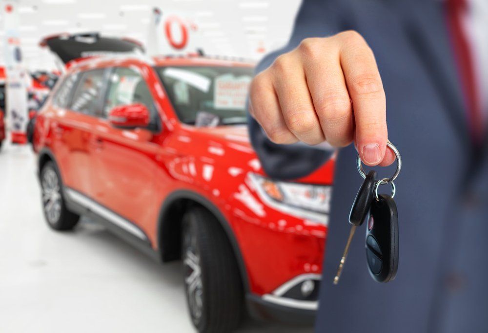 Person in a Suit Holding Car Keys in Front of a Red SUV — Albury Super Cheap Car Rentals in Lavington, NSW