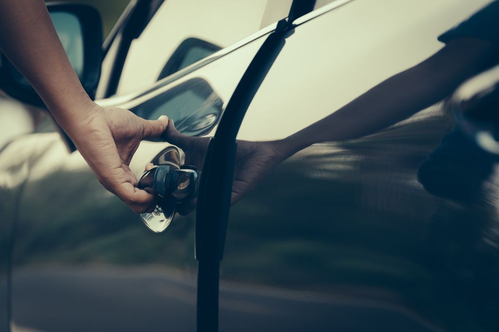 Person's Hand Opening a Car Door Handle on a Reflective — Albury Super Cheap Car Rentals in Lavington, NSW