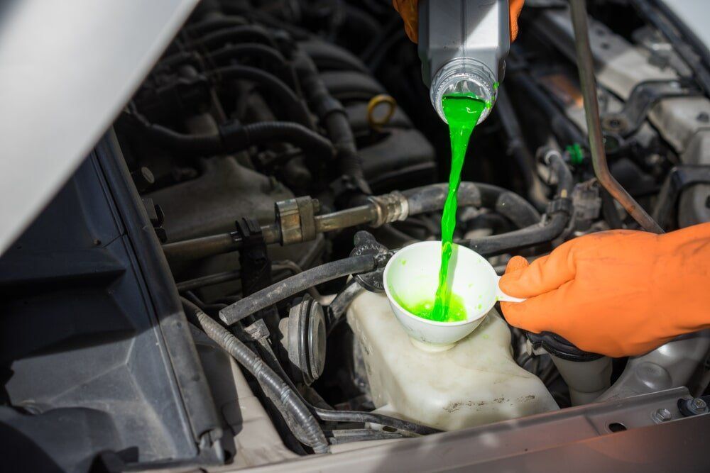 Person Pouring Green Coolant Into a Car's Radiator Reservoir — Albury Super Cheap Car Rentals in Lavington, NSW