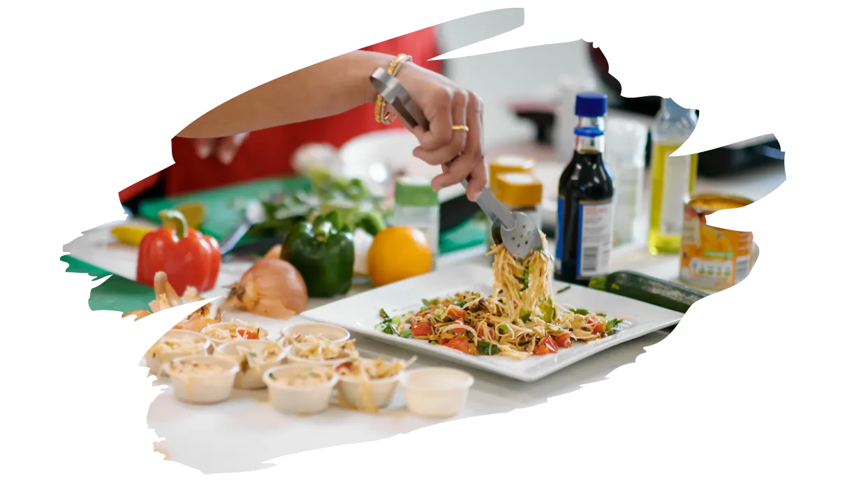 A person is cutting vegetables into noodles on a plate.