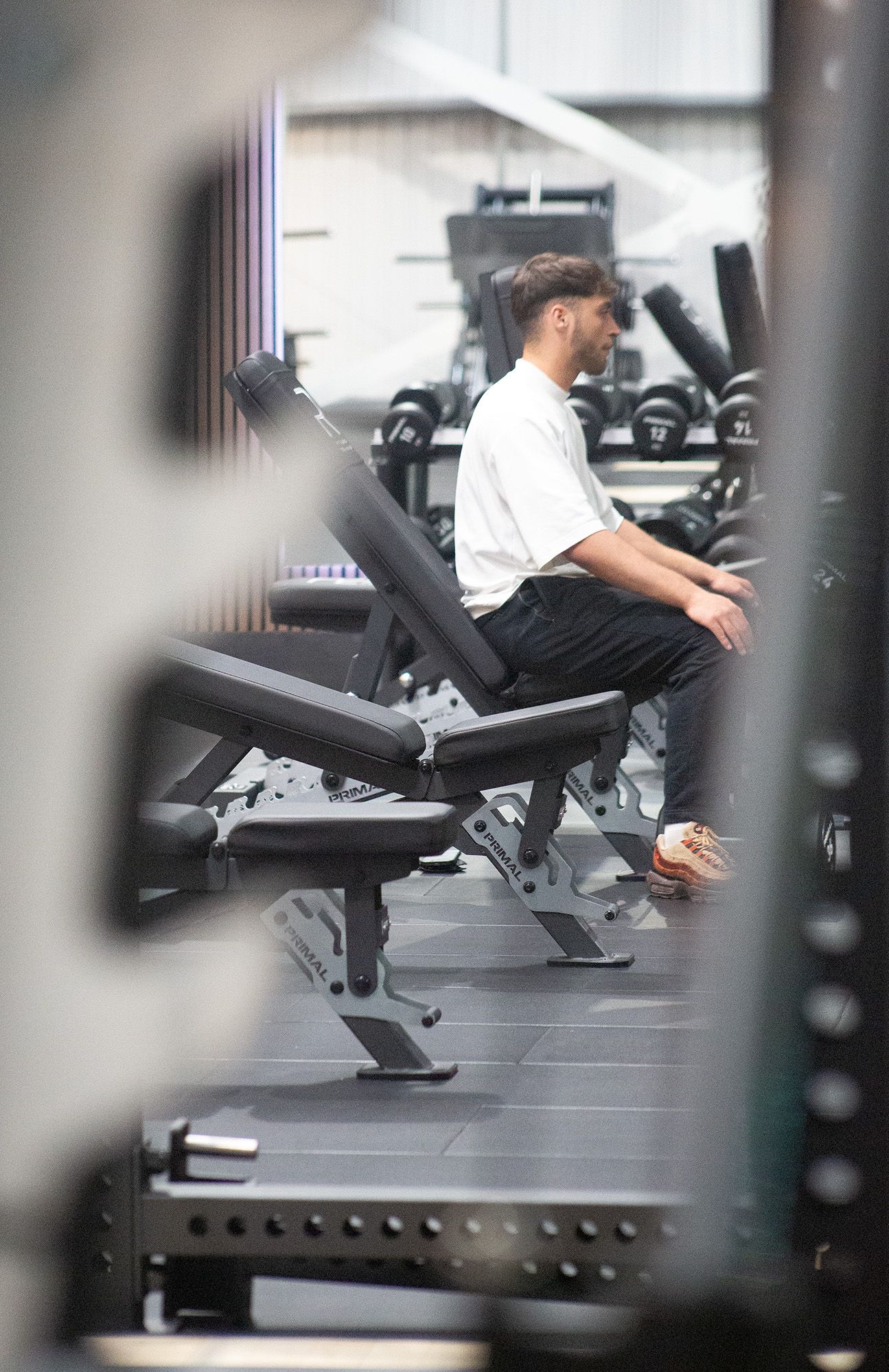 A man is sitting on a bench in a gym.