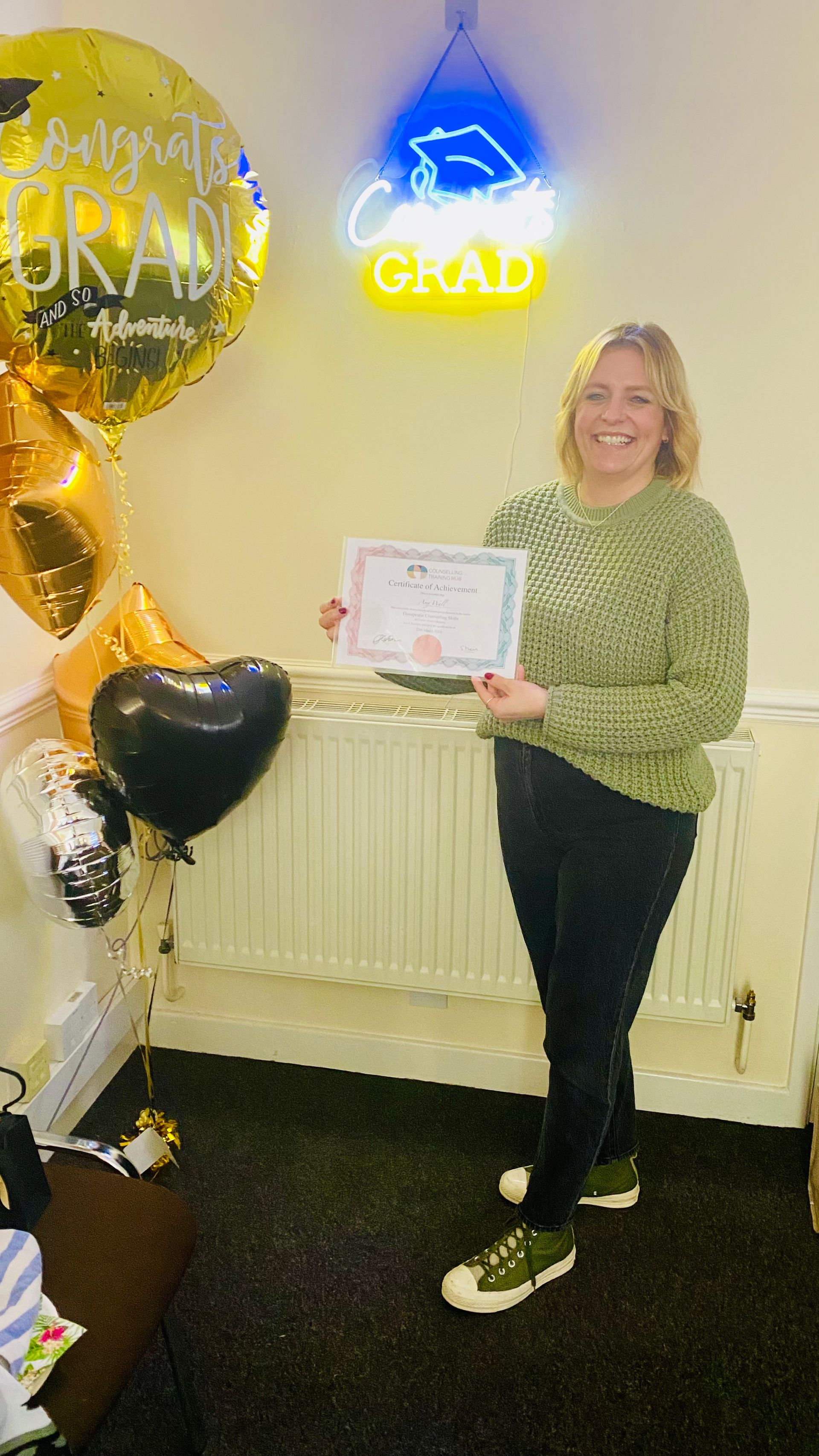 Woman holding a certificate, celebrating graduation with balloons and a 