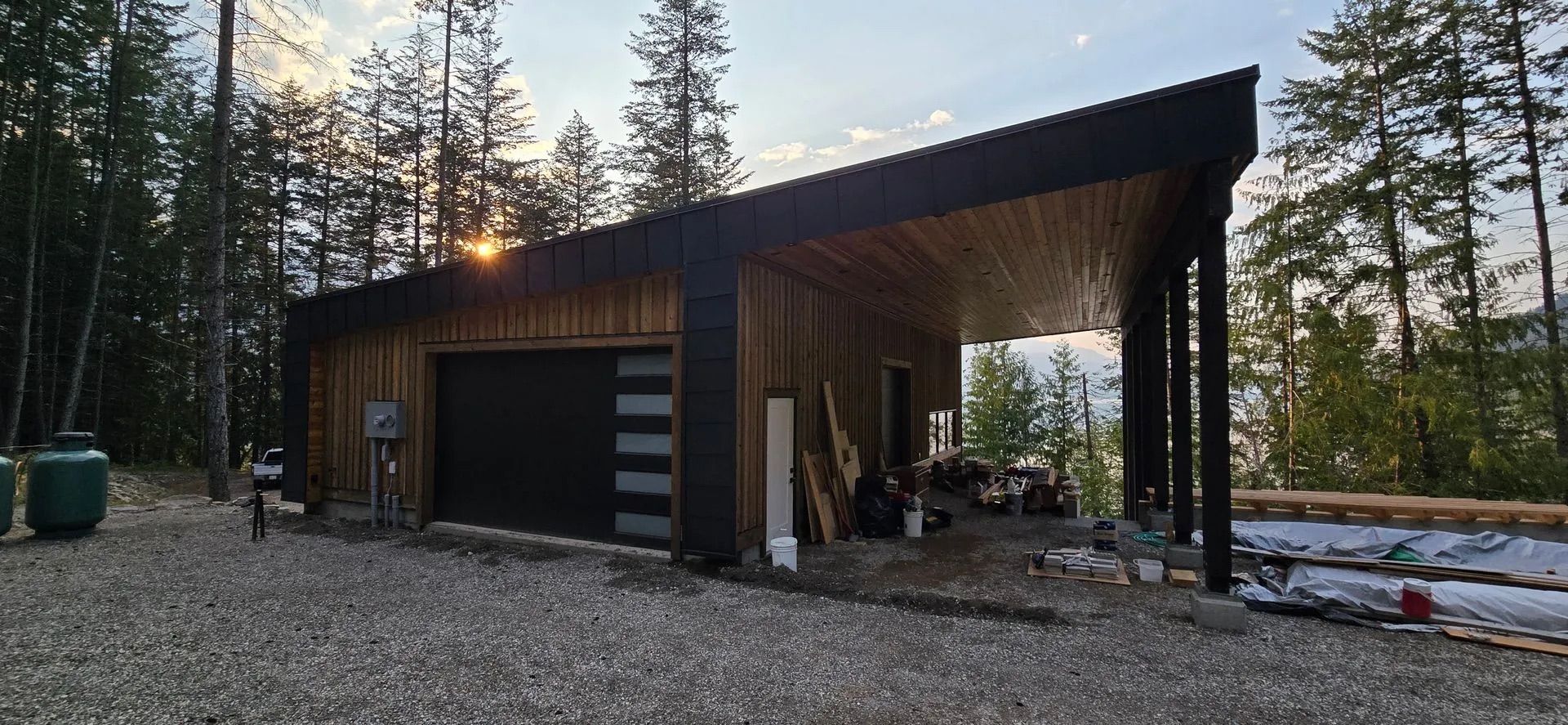 Modern dark-wood garage or cabin in a snowy forest at sunset