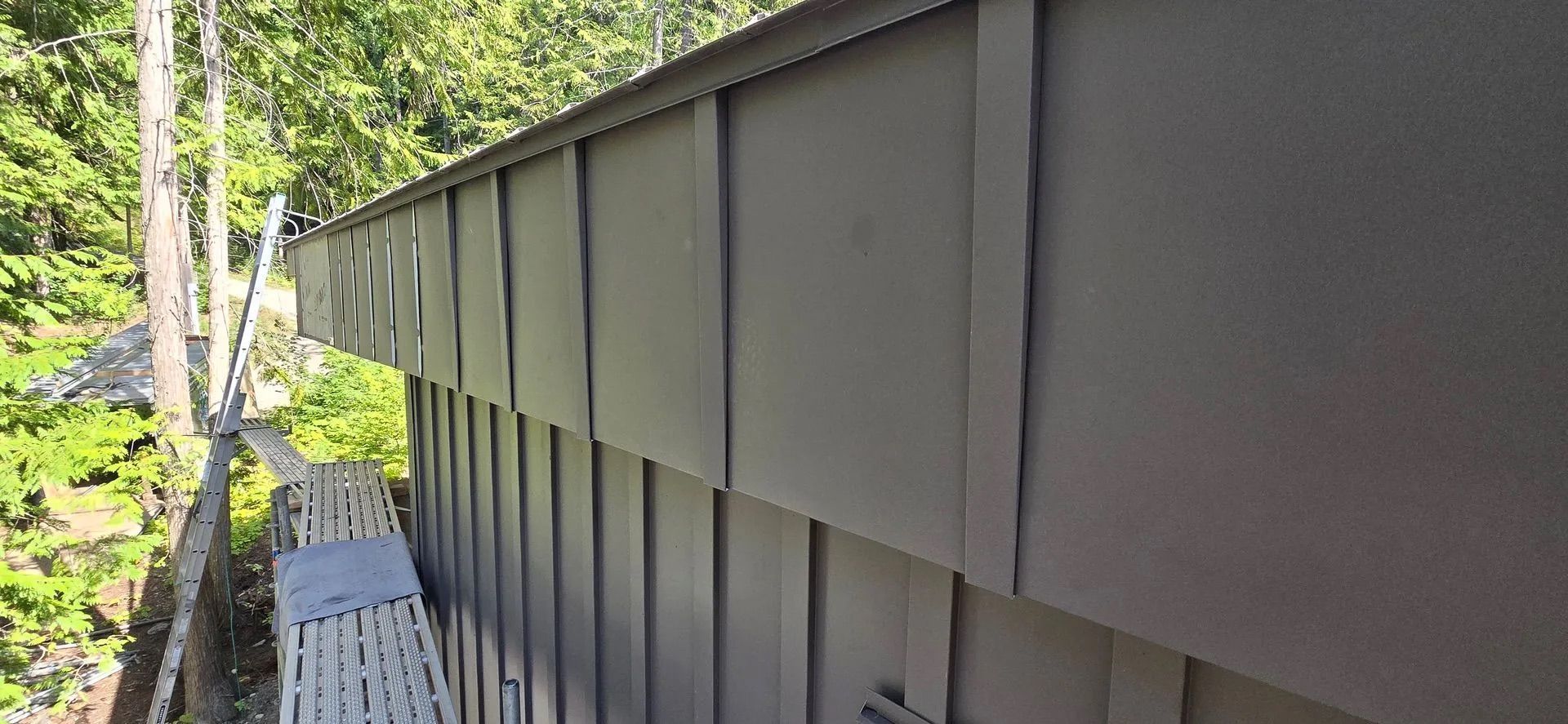 Side view of a gray metal fence along a wooded path beside a railing