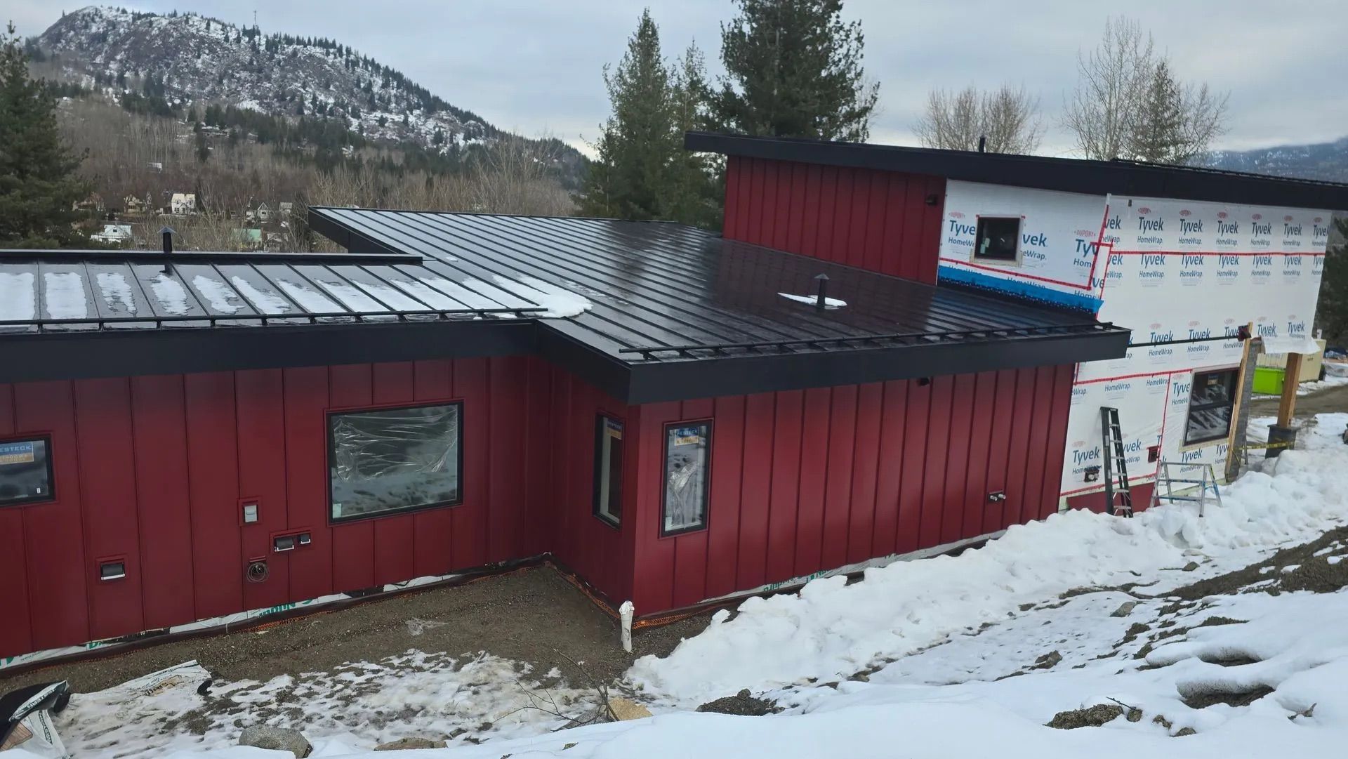 Red building with dark roof on a snowy hillside, with mountains in the background
