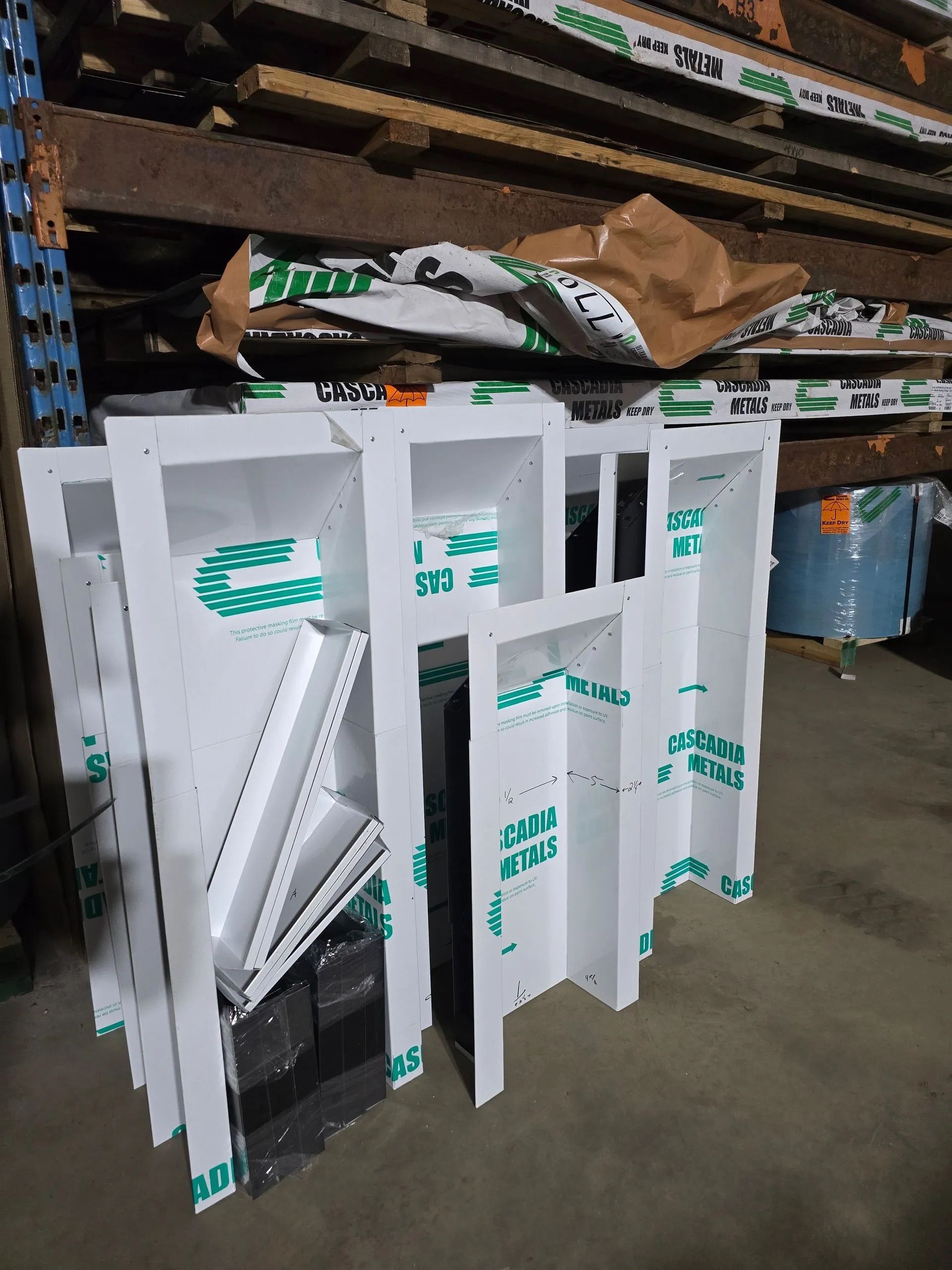Stacked white and green foam board signs in a warehouse aisle, leaning against a shelf.
