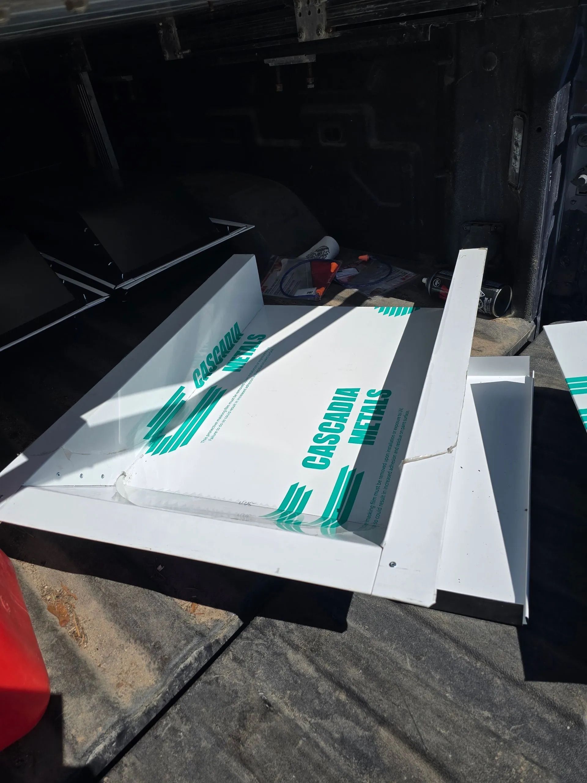 White insulated panel boards stacked in a dark truck bed, with teal straps and labels visible.