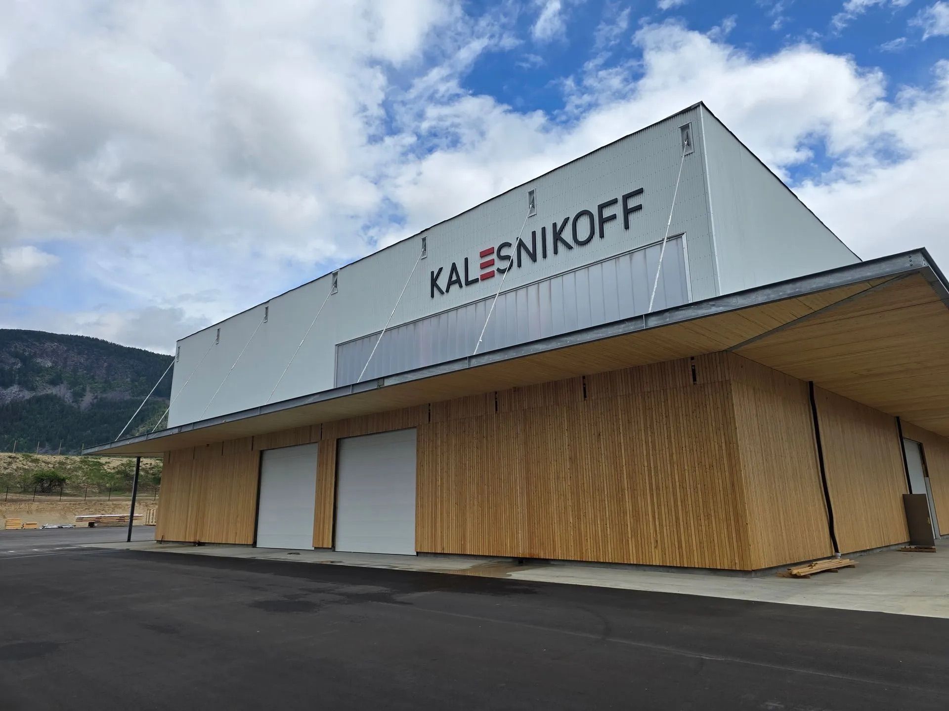 Kallesnikkoff building with wood facade and large white sign under a cloudy sky