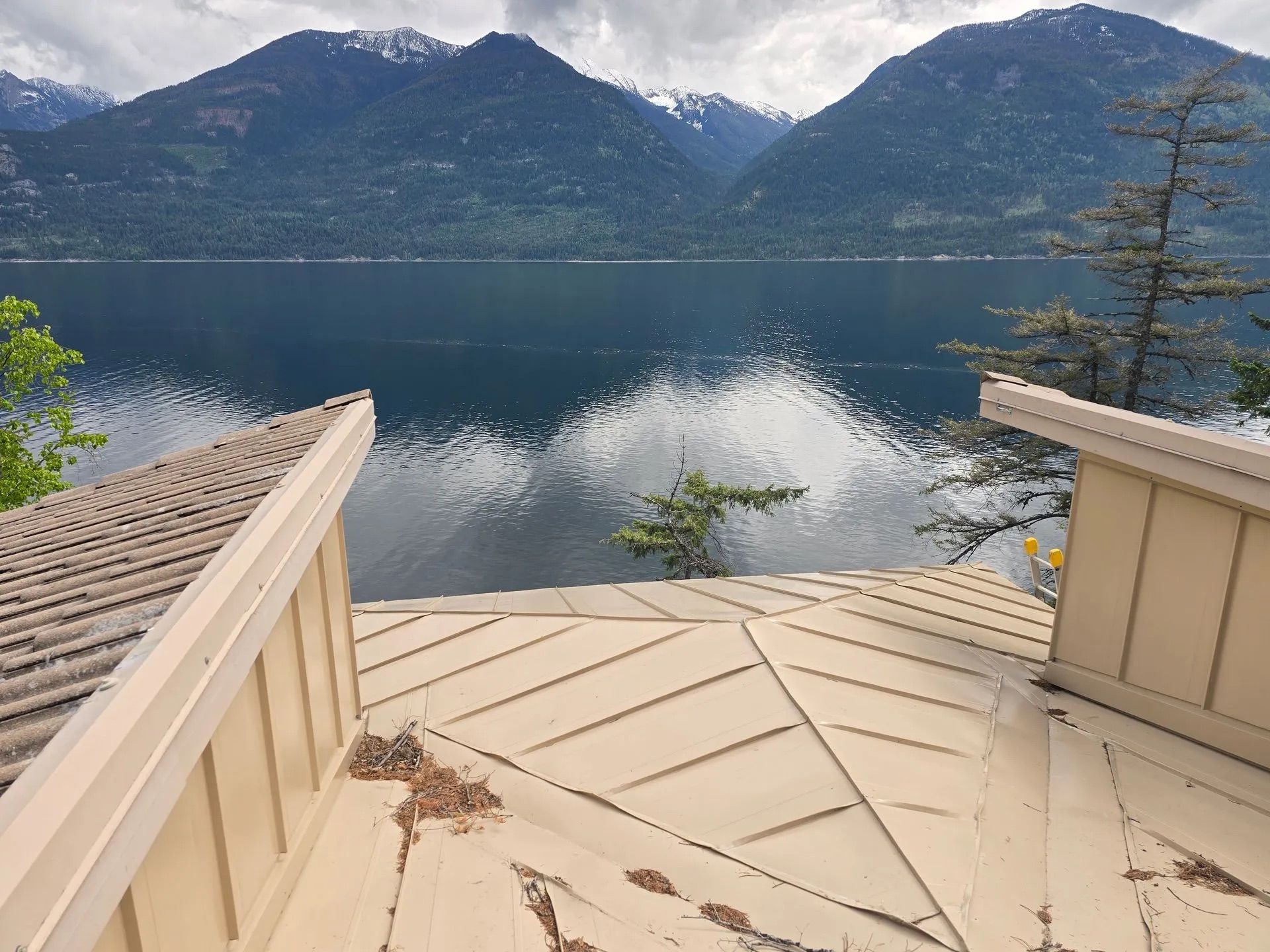 Lake view from a deck with mountains and trees reflected in calm water