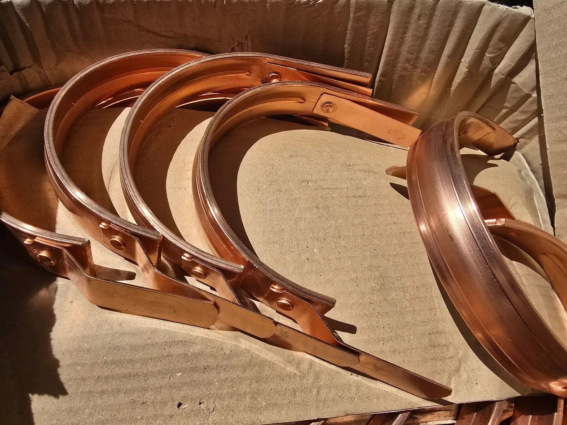 Several copper-colored metal rings stacked in a cardboard box