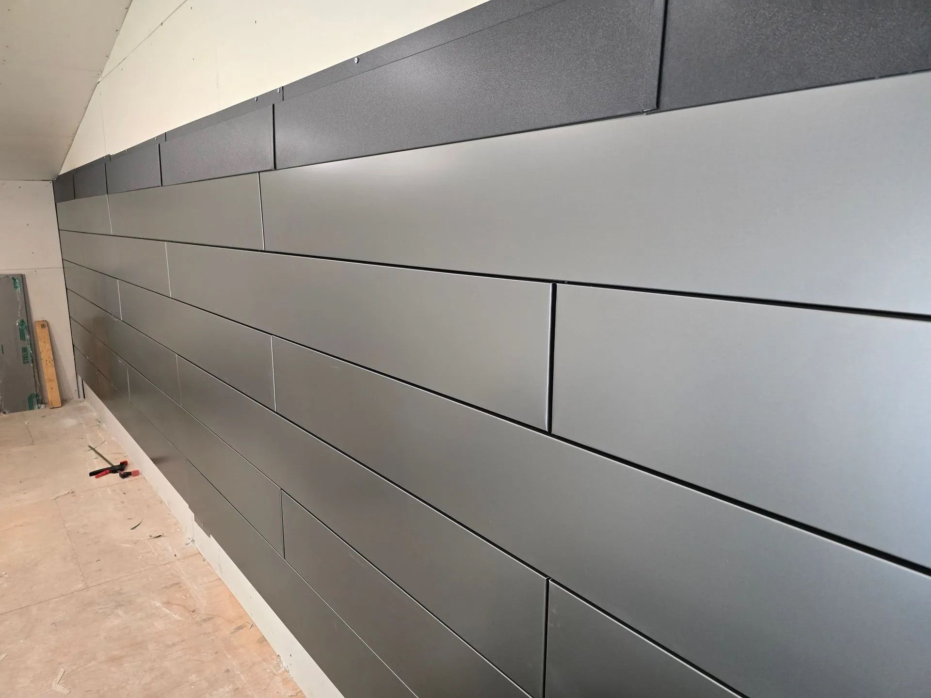 Long gray wall panels in a hallway with a light floor and dark top trim