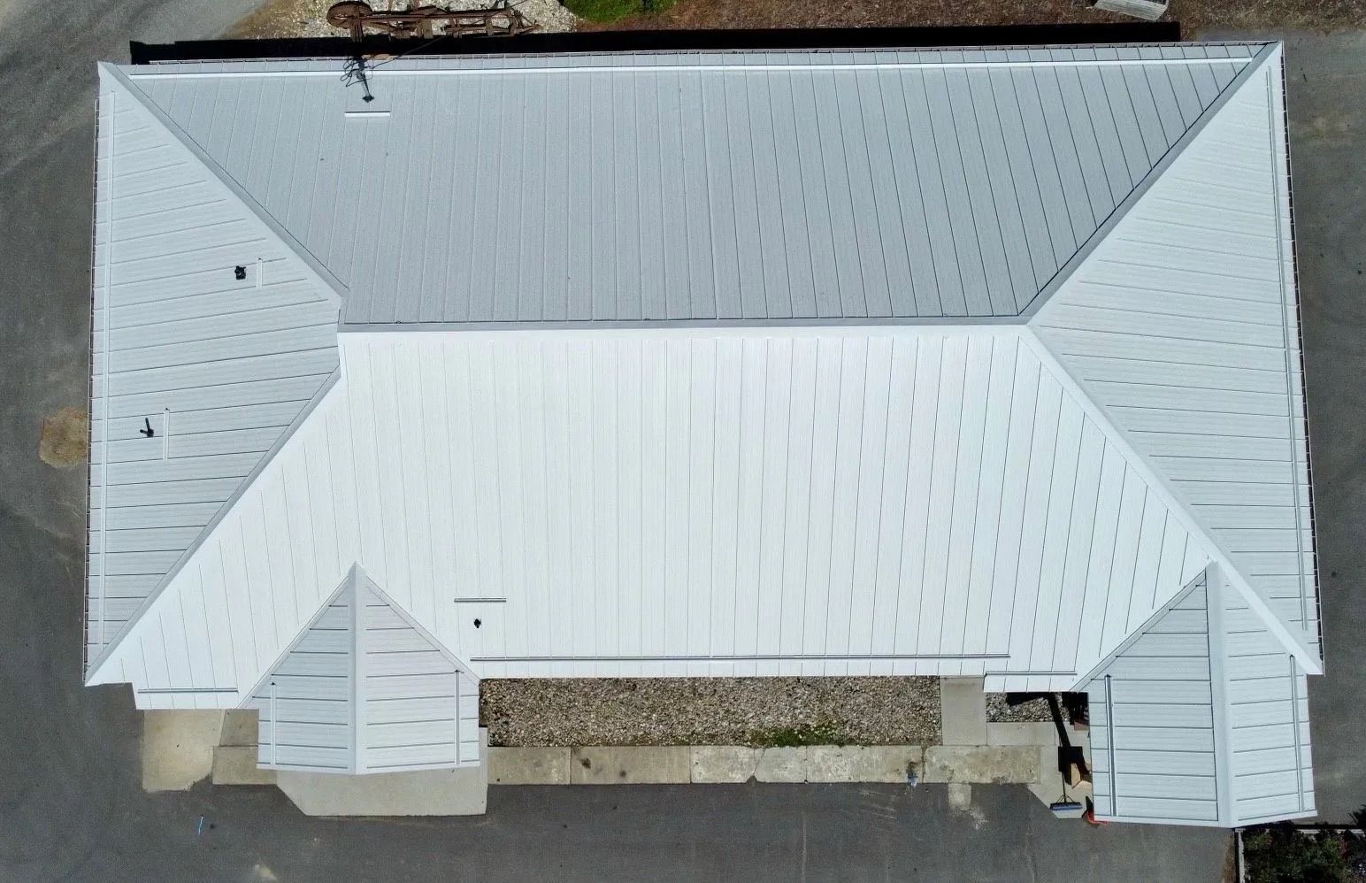 Aerial view of a white-roofed house with two front porches and surrounding driveway.