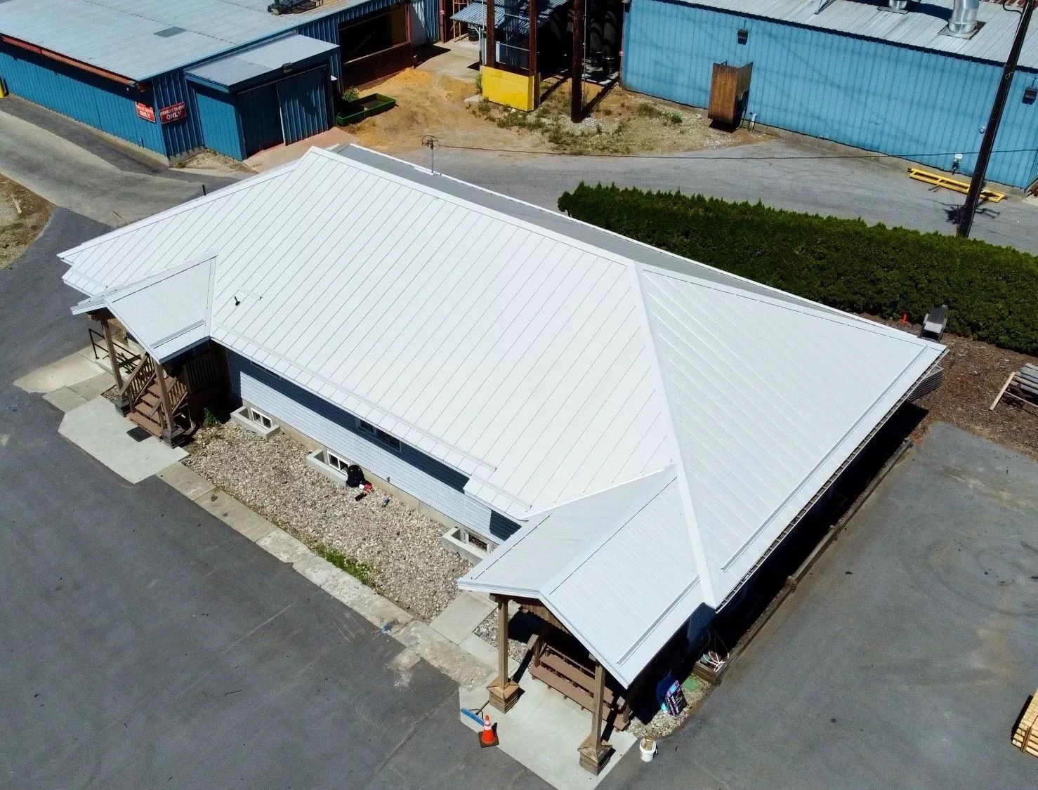 Aerial view of a white-roofed building with blue walls and a small covered entrance.