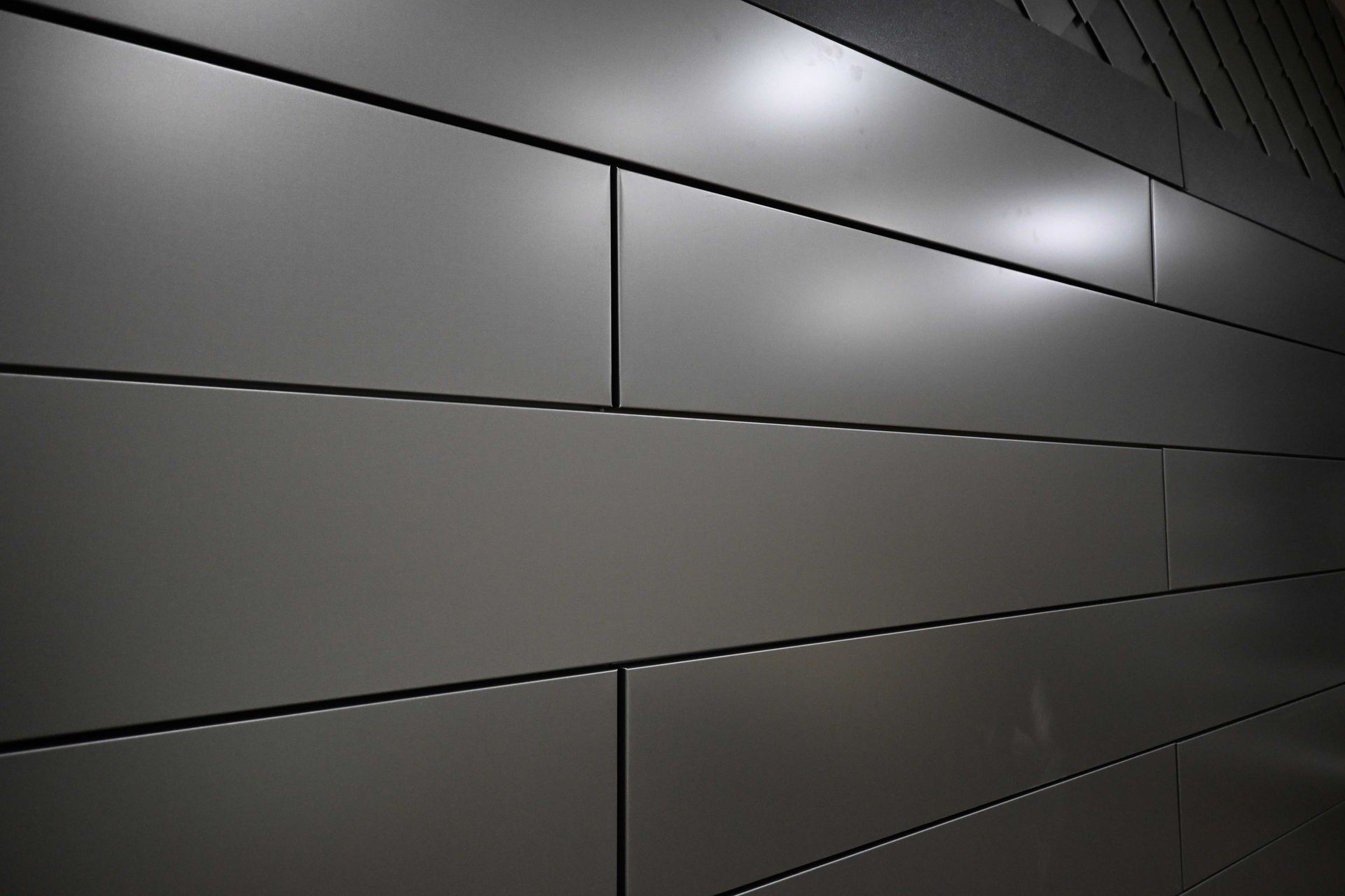 Close-up of gray metal wall panels with horizontal seams and glossy reflections