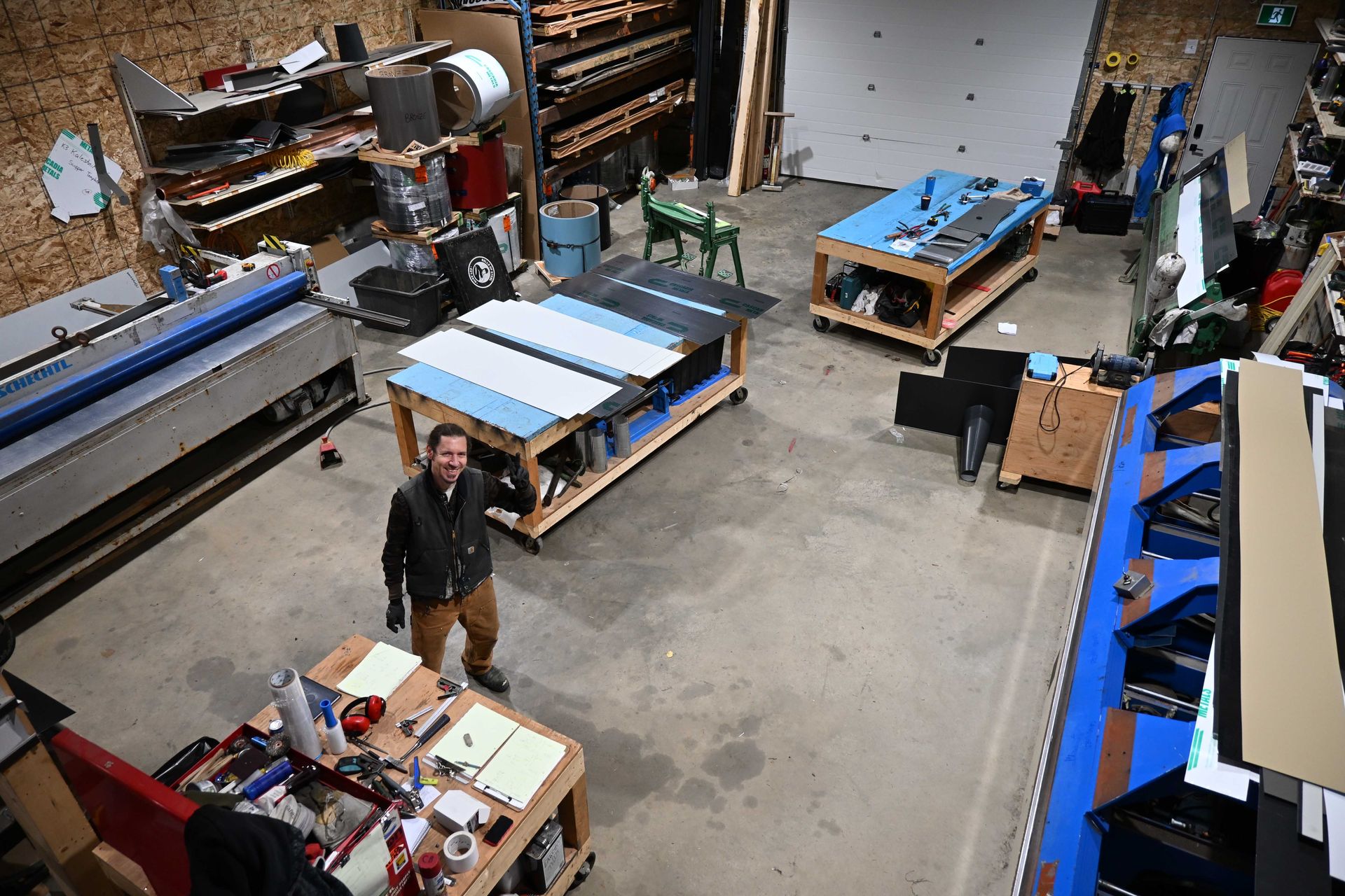 Large workshop with several blue tables and one person standing near a workbench.