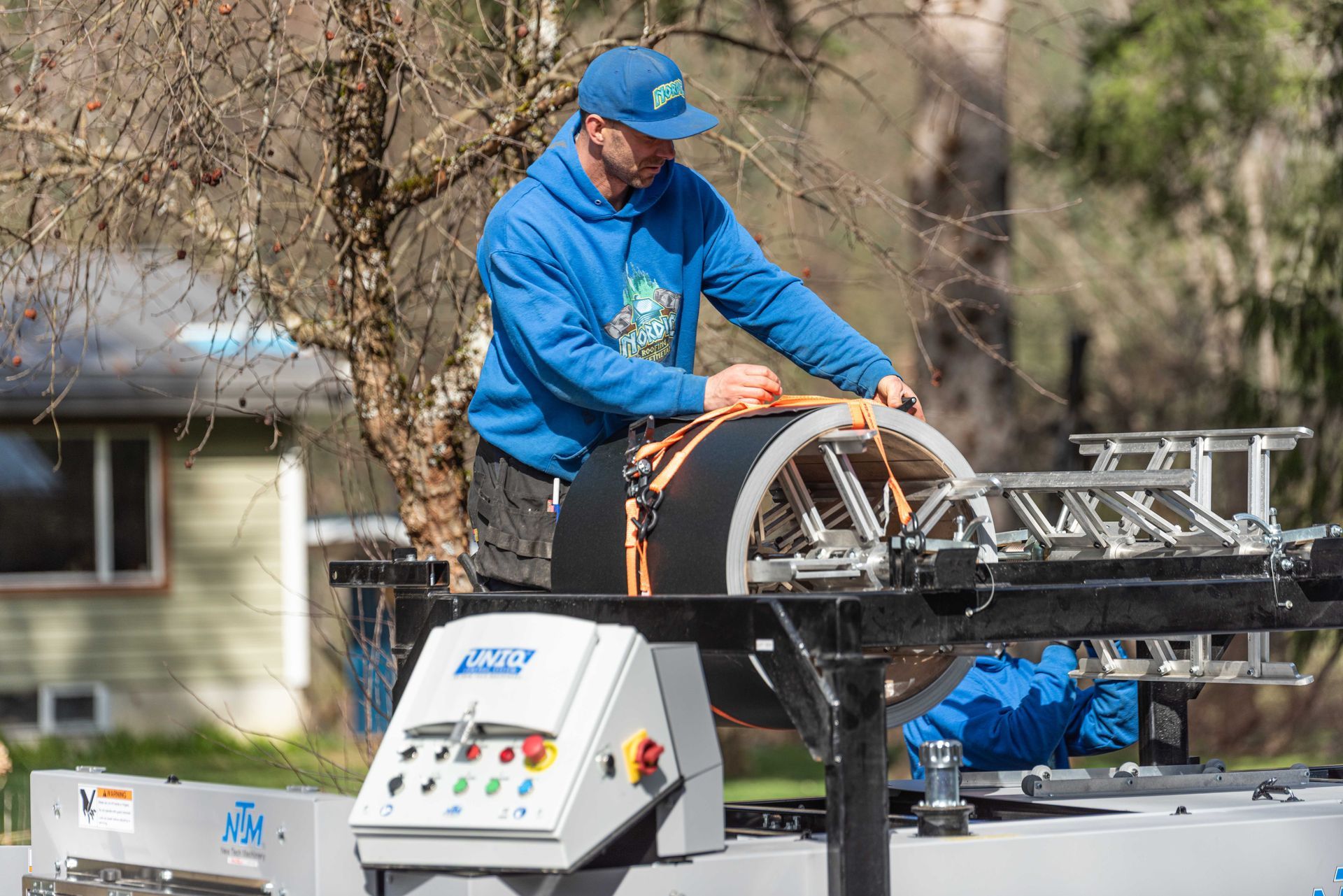 Worker in blue jacket operating equipment on a truck-mounted platform outdoors
