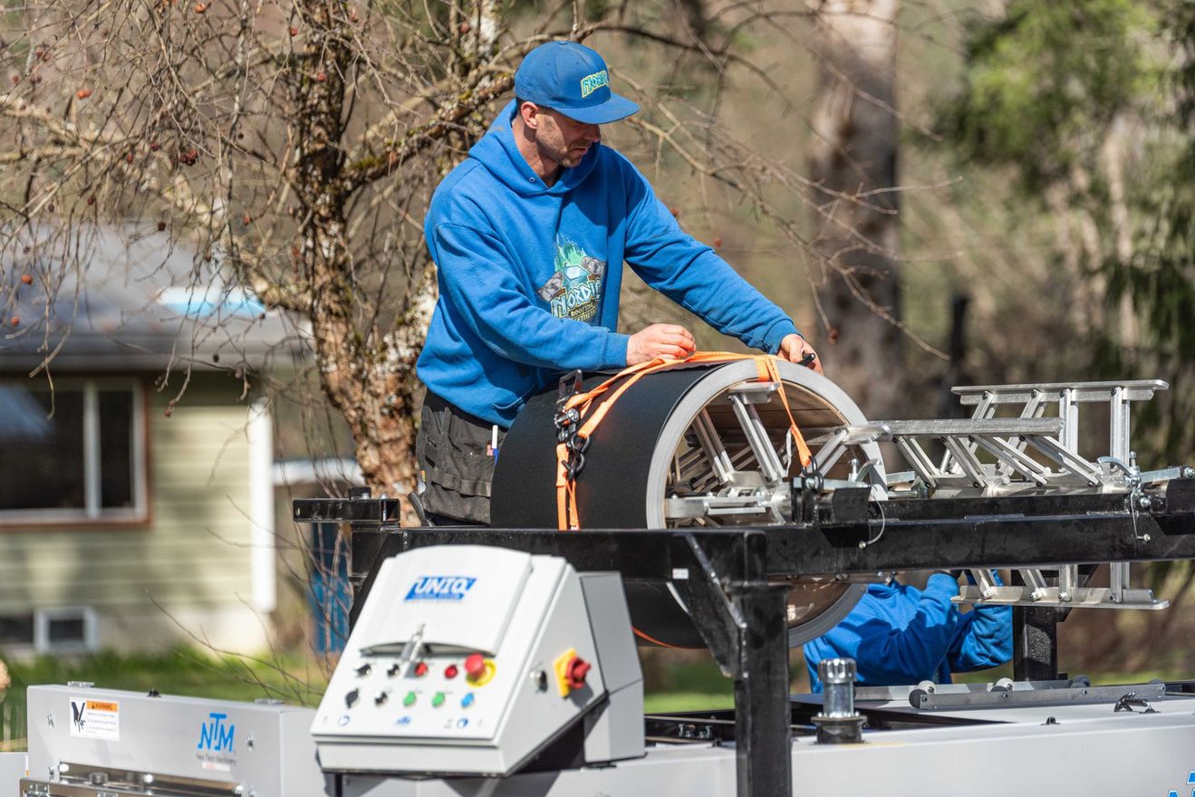 Worker in blue jacket operating rooftop equipment on a truck-mounted platform outdoors