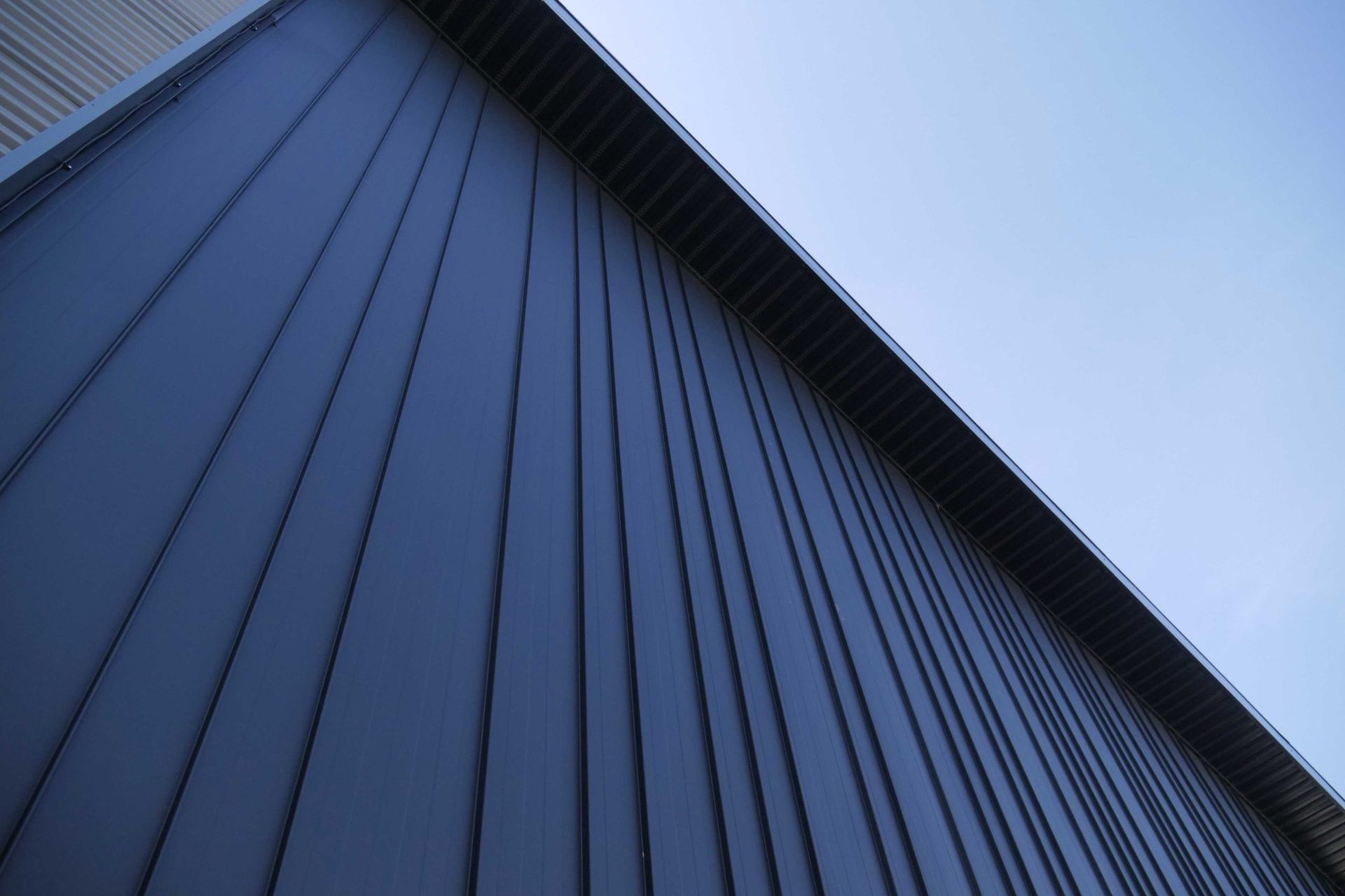 Low-angle view of a blue corrugated metal building against the sky