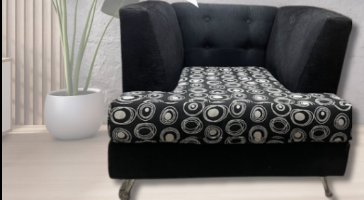 Silla con estampado en blanco y negro, con respaldo alto y reposabrazos, situada junto a una planta y una ventana.
