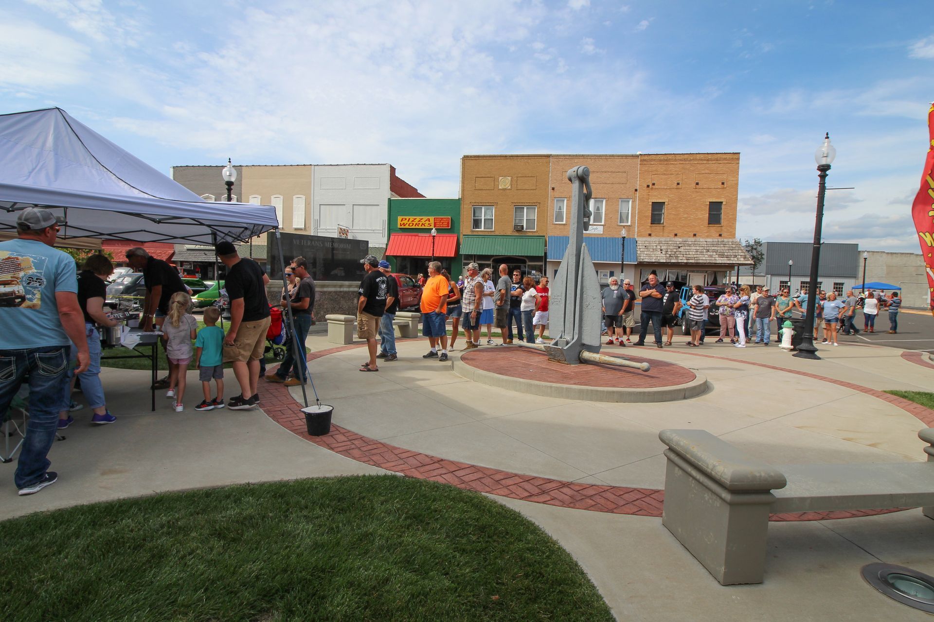Brick building with black roof, dormers, and arched windows beneath a blue sky and tree branches.