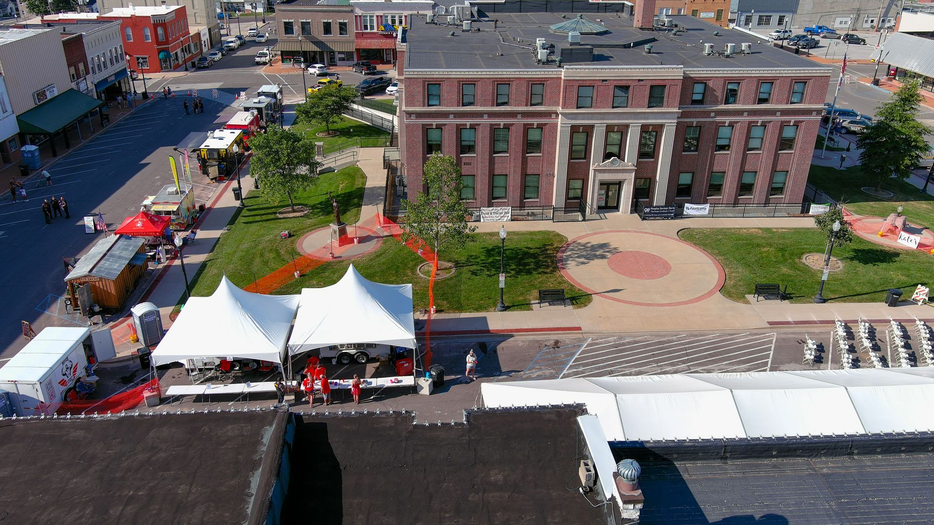 Brick building with black roof, dormers, and arched windows beneath a blue sky and tree branches.