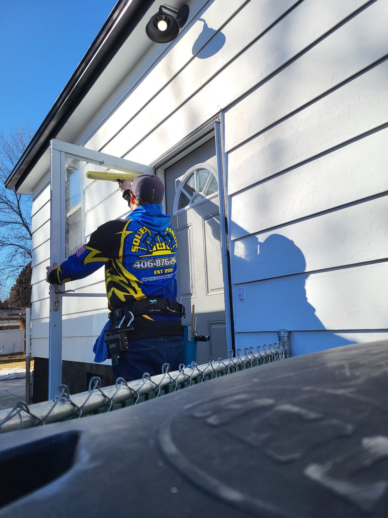 A man wearing a blue and yellow shirt with a tiger on the back is working on a door