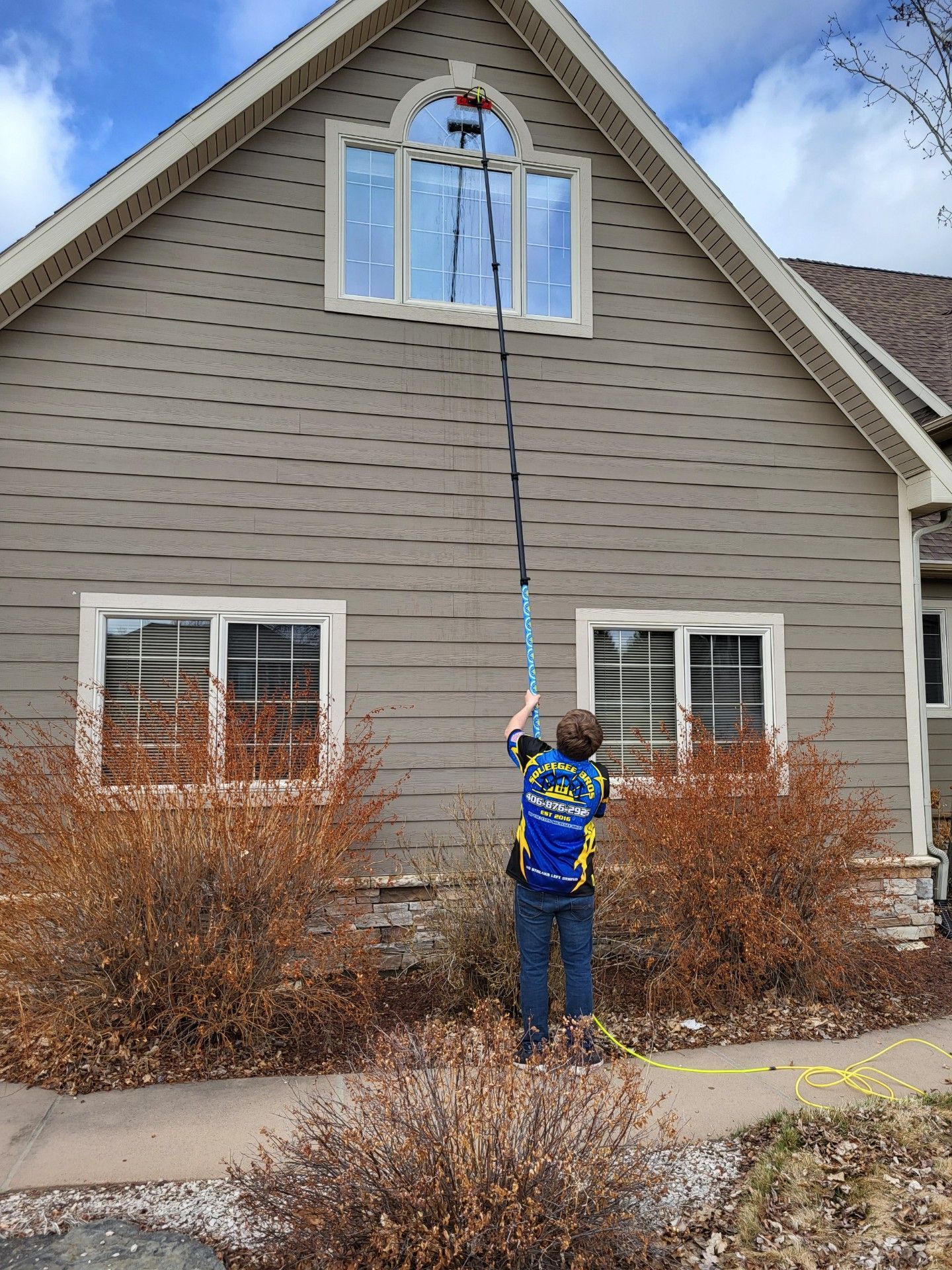 A man is cleaning a window with a hose and a ladder