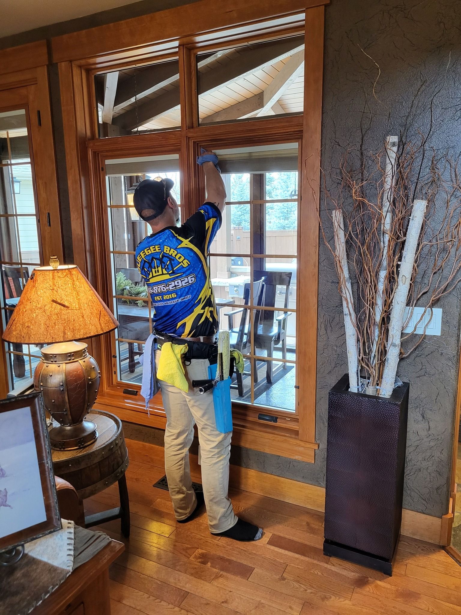 A man is cleaning a window in a living room