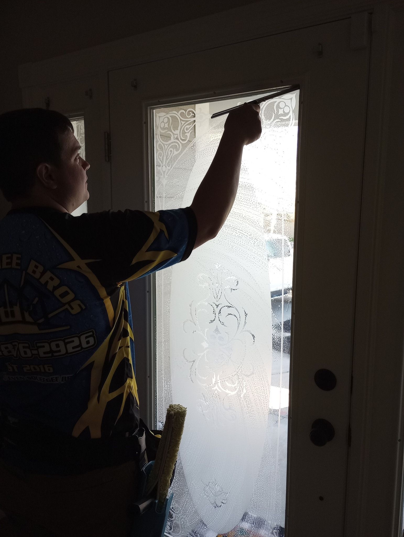 A man is cleaning a window with a brush.