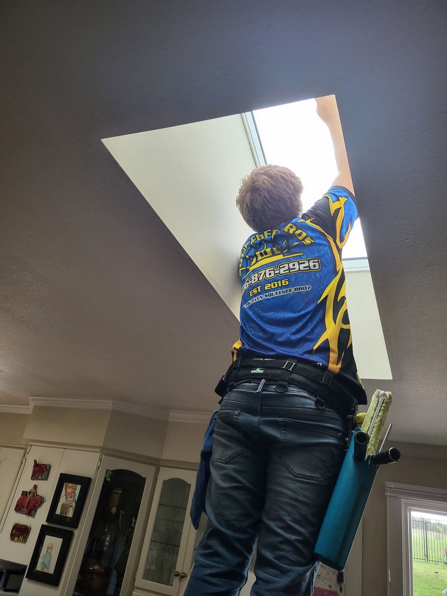A man is cleaning a skylight in a living room