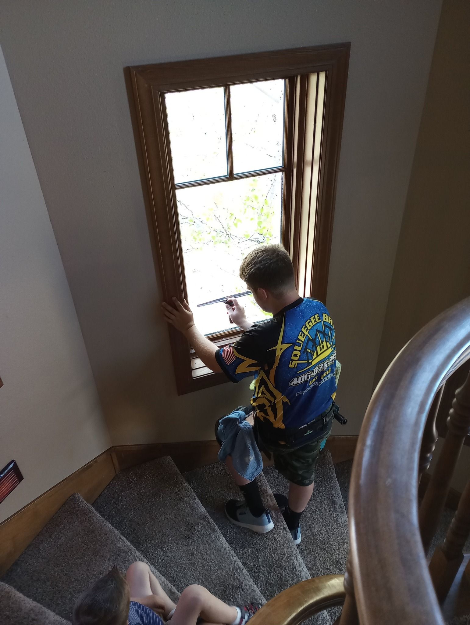 A man is cleaning a window on a spiral staircase.