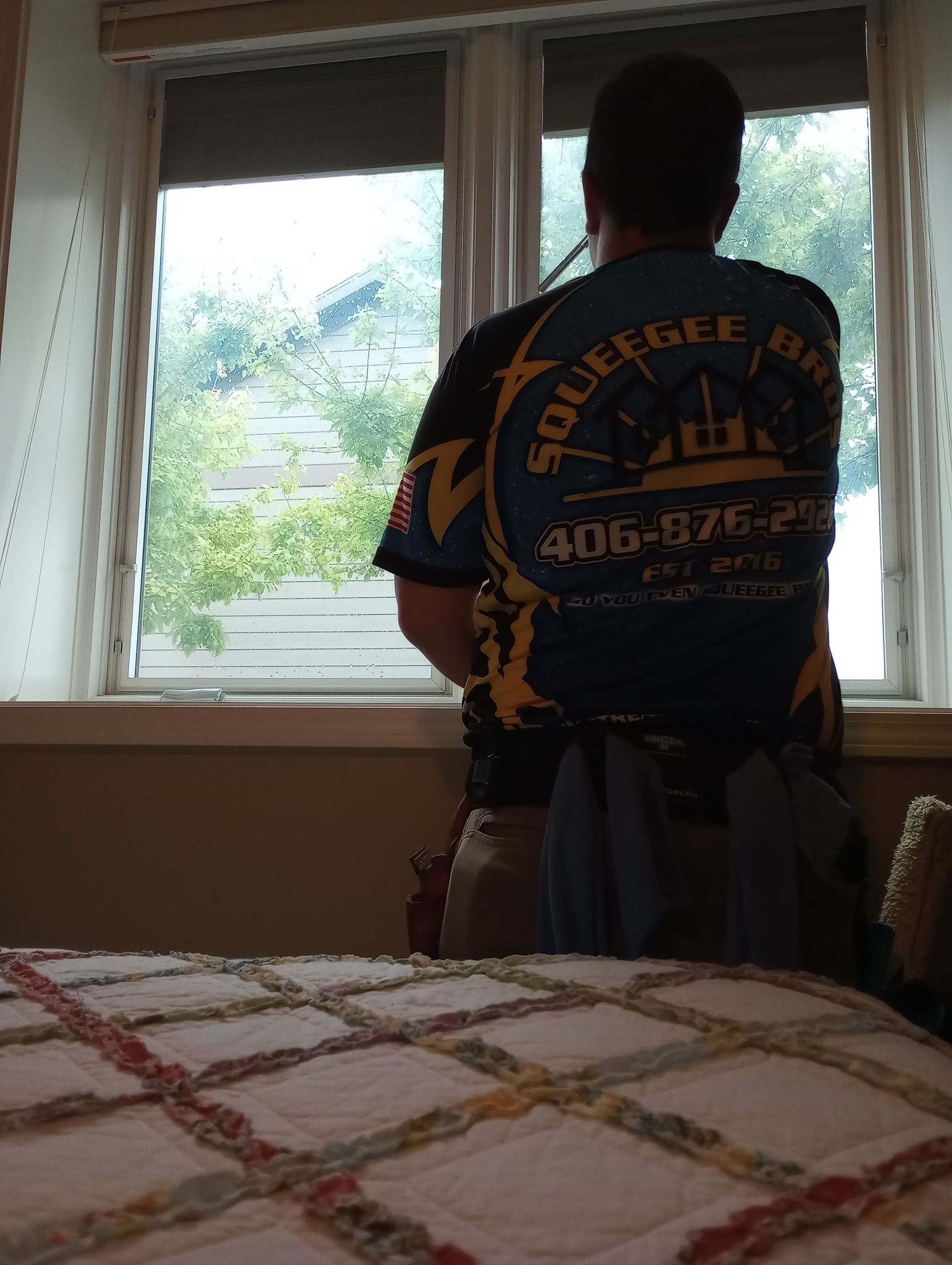 A man standing in front of a window wearing a shirt that says squeegee