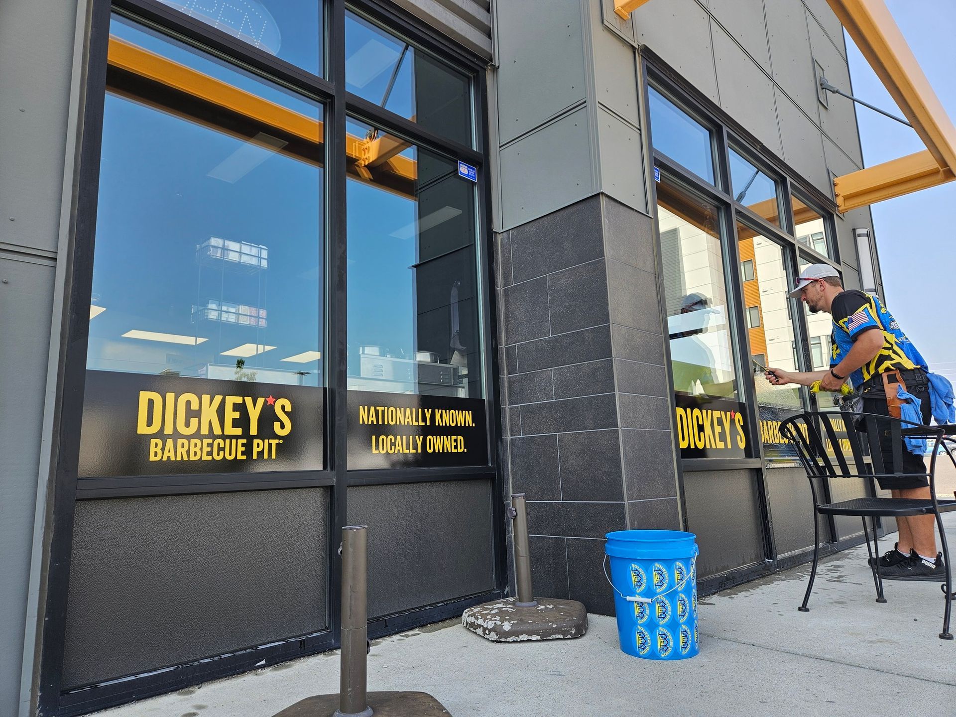 A man cleaning the windows of a building that says dickey 's barbeque fit