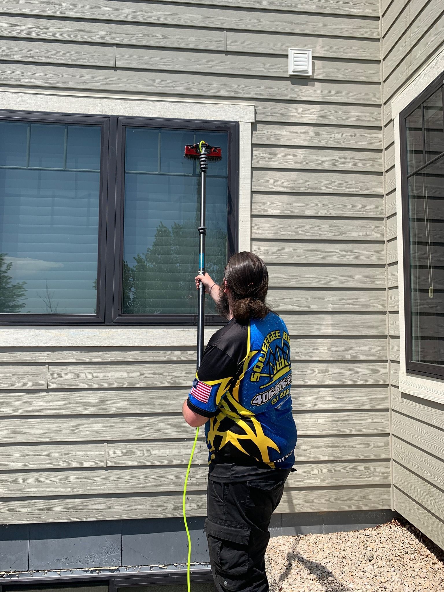 A man is cleaning a window with a hose.