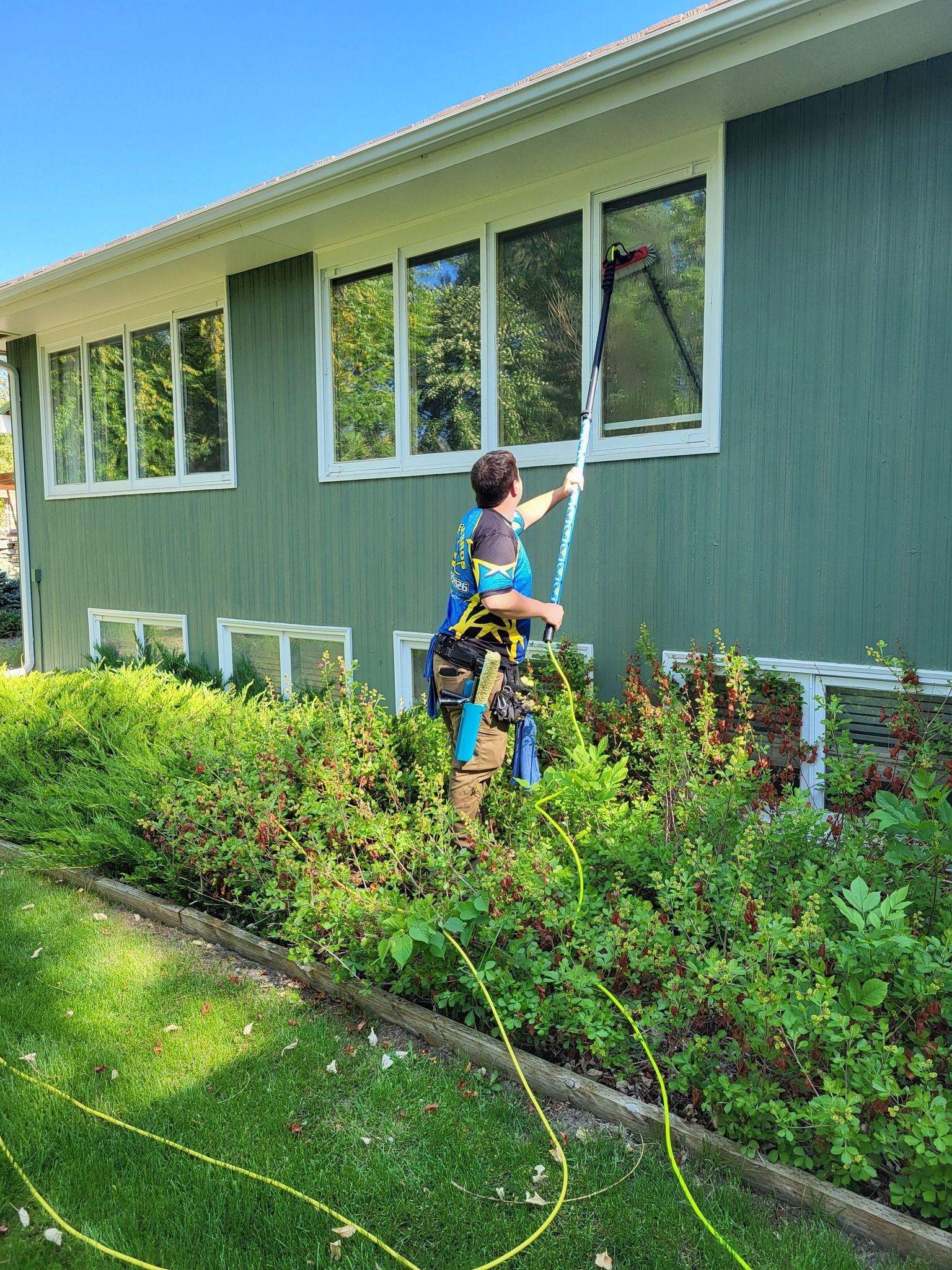A man is cleaning the windows of a green house