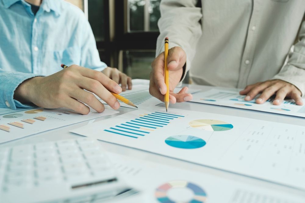 Two people reviewing business reports with graphs and charts.