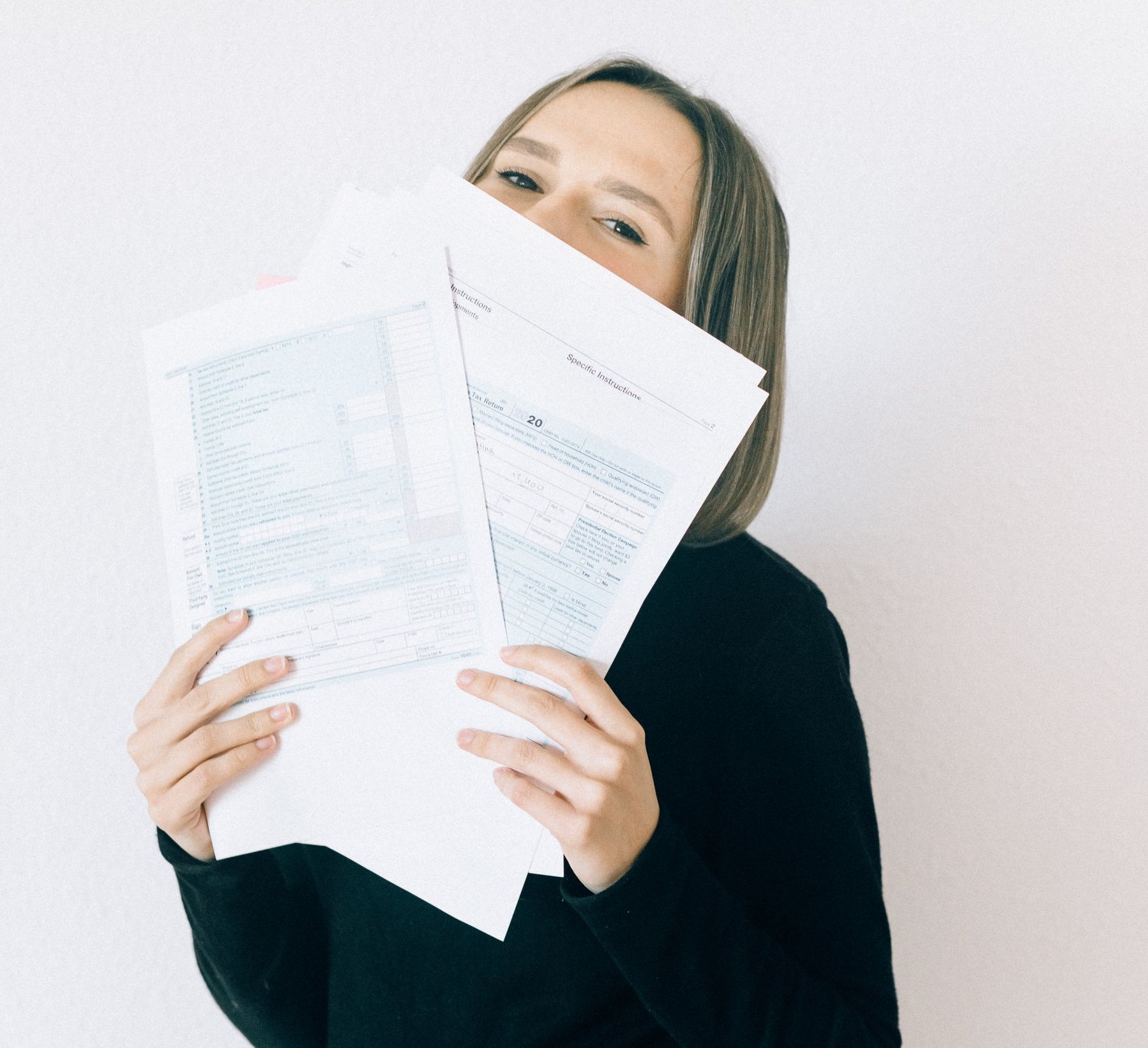 picture of woman in black sweater holding tax forms