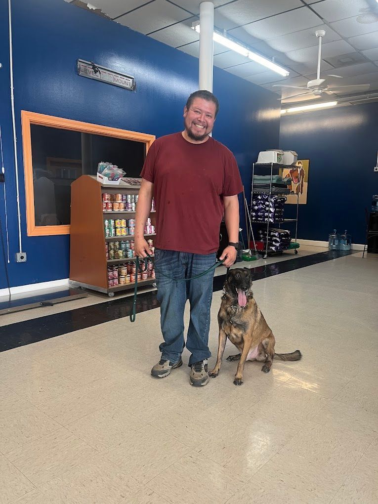 A man is standing next to a dog in a room.