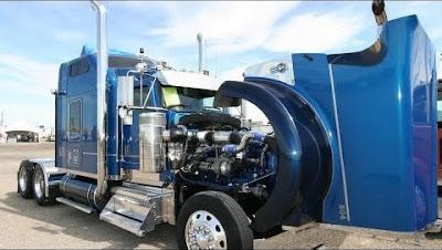 A blue semi truck with its hood open is parked on the side of the road.