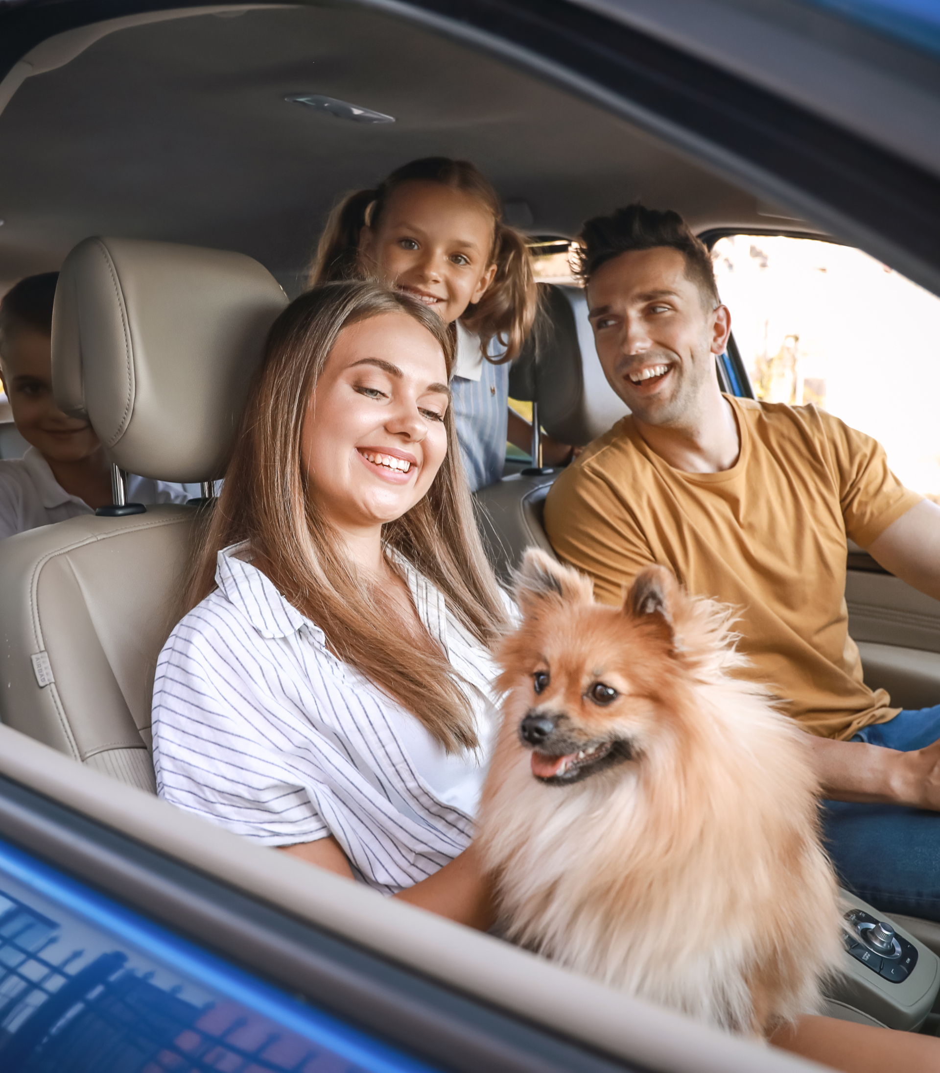 a family sits in a car with their dog