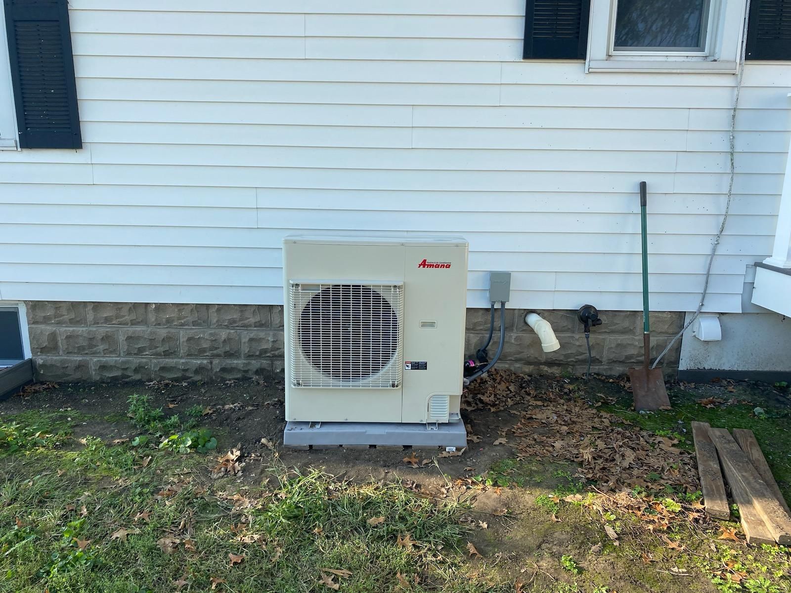 A man and a woman are sitting on a couch in front of an air conditioner.