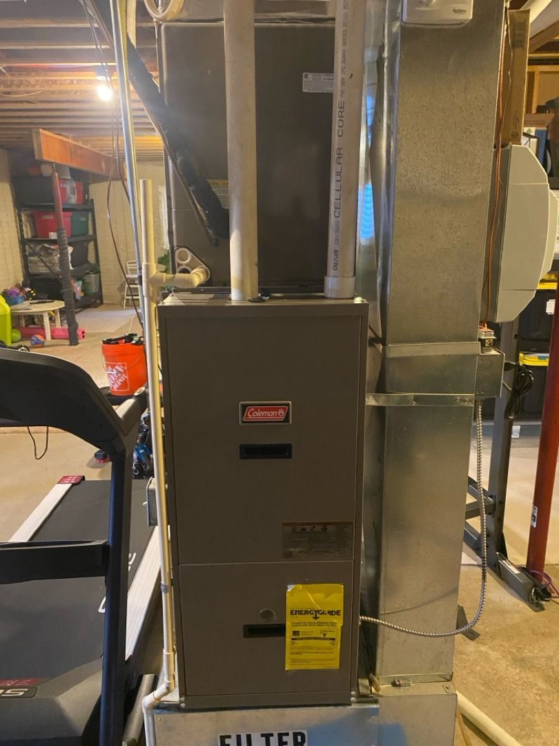 A man is installing an air conditioner on a brick wall in a living room.