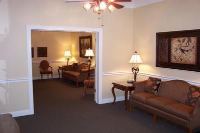 A living room with a couch , chairs , lamps and a ceiling fan.