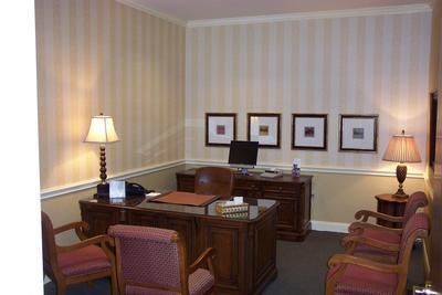 A waiting room with a desk chairs and lamps