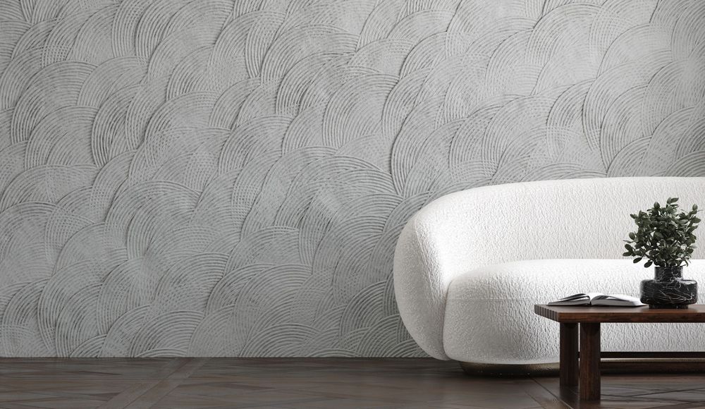 Soggiorno minimalista con parete grigia texturizzata, divano bianco e tavolino in legno con pianta.