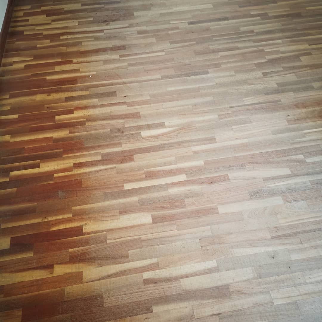 Assi di legno del pavimento con calde tonalità marroni e luce solare che crea un bagliore luminoso sulla superficie