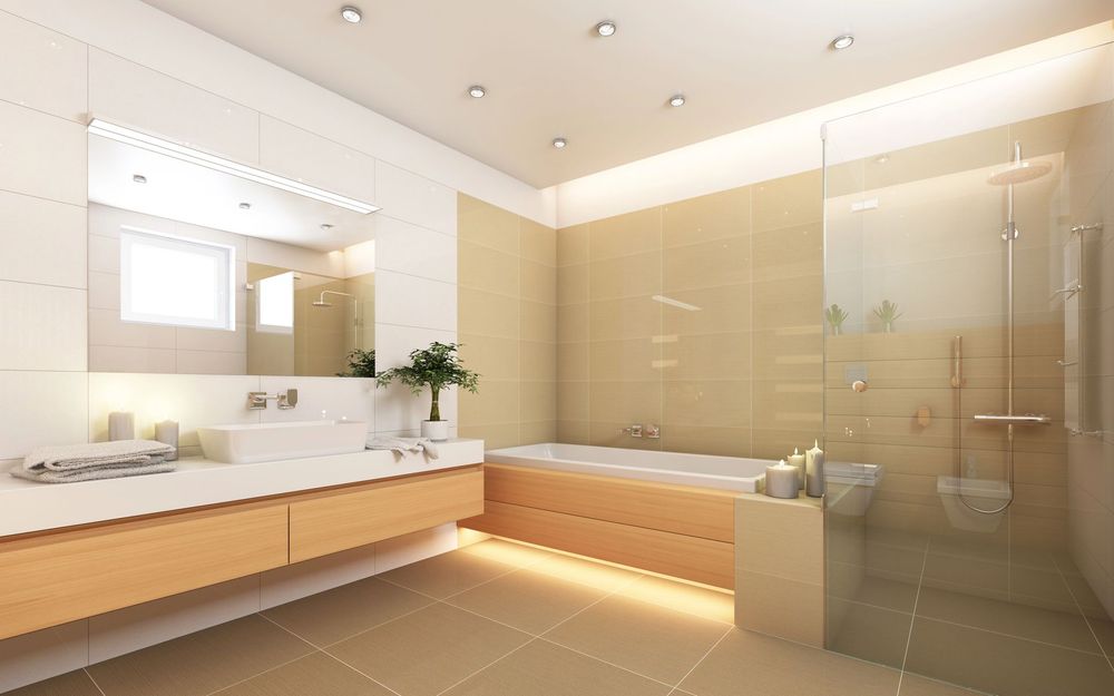 Luminoso bagno moderno con doppio lavabo, ampio specchio, vasca da bagno e pareti rivestite con piastrelle beige.